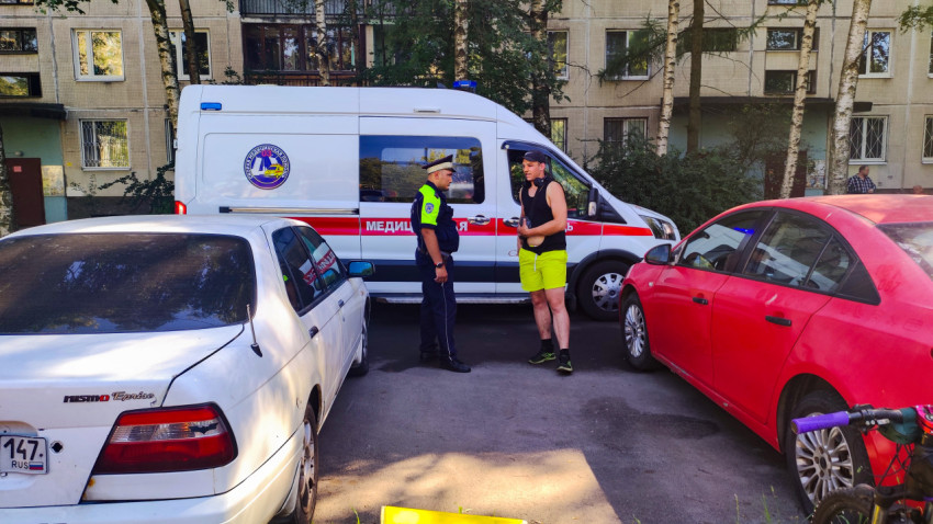 Инспектор ДПС разговаривает с мужчиной на фоне автомобиля скорой помощи во дворе