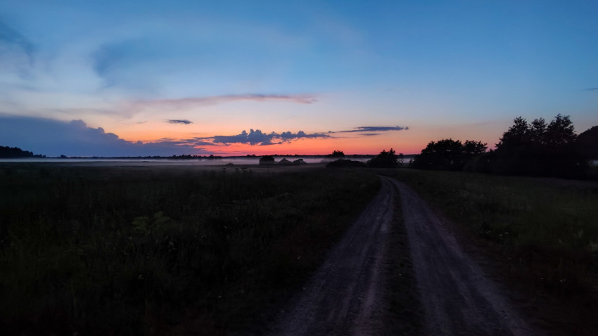 Широкий вечерний пейзаж с просёлочной дорогой, туманом и большим небом