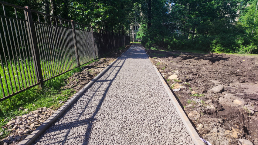 Щебёночное основание пешеходной дорожки у металлического забора
