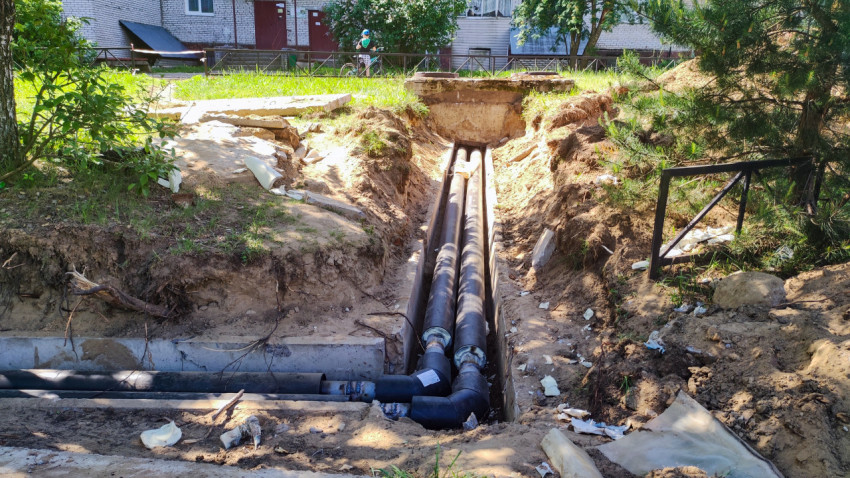 Траншея с теплоизолированными трубами в бетонном лотке во дворе жилого дома