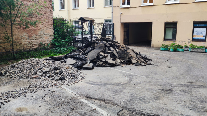 Куча демонтированного асфальта и щебня во дворе у арочного проезда