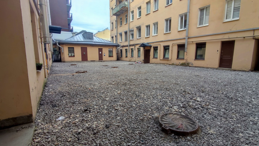 Люк инженерных коммуникаций на щебёночной площадке во дворе жилого дома