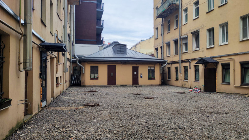 Гравийный двор-колодец с одноэтажной хозяйственной постройкой и люками коммуникаций