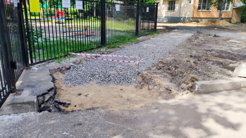 Участок дорожных работ у ворот с отсыпкой щебнем и сигнальной лентой