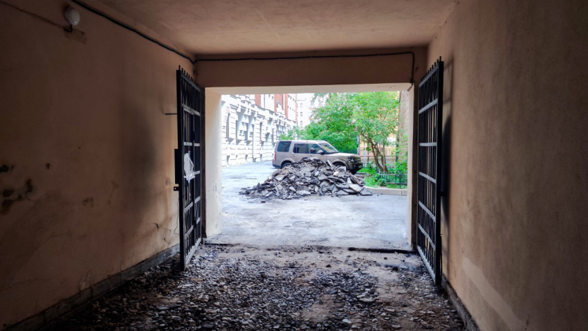 Вид из подворотни на двор с кучей строительного мусора и припаркованным внедорожником