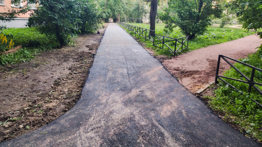 Свежий асфальтовый тротуар в зелёном дворе с ответвлением дорожки