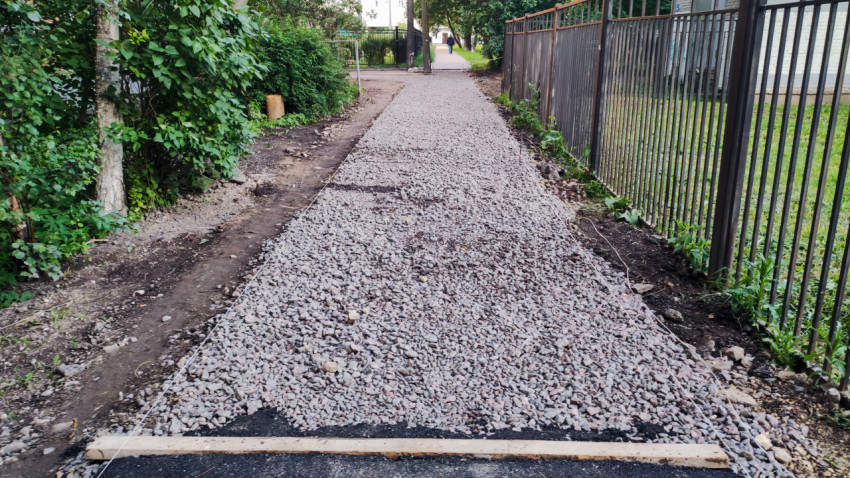 Щебёночная подушка под тротуар с разметкой шнуром у металлического забора