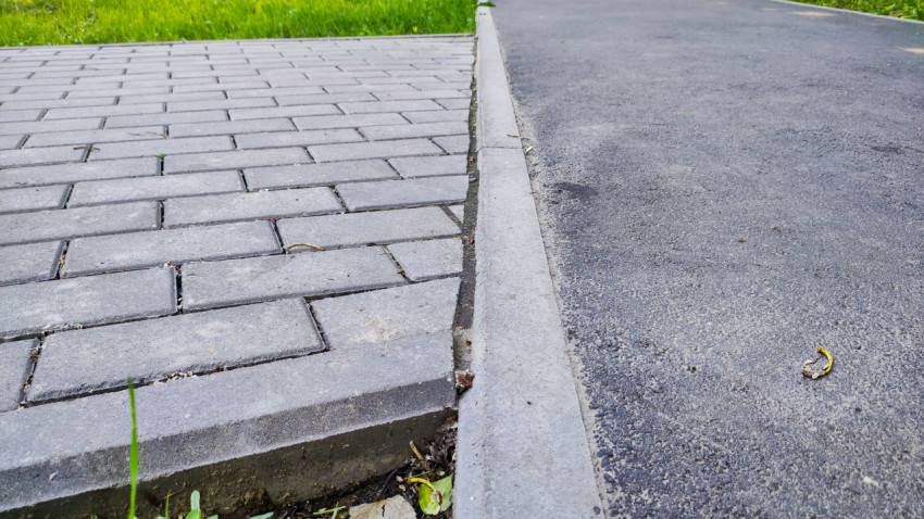 Крупный план бордюра между тротуарной плиткой и асфальтом на пешеходной дорожке