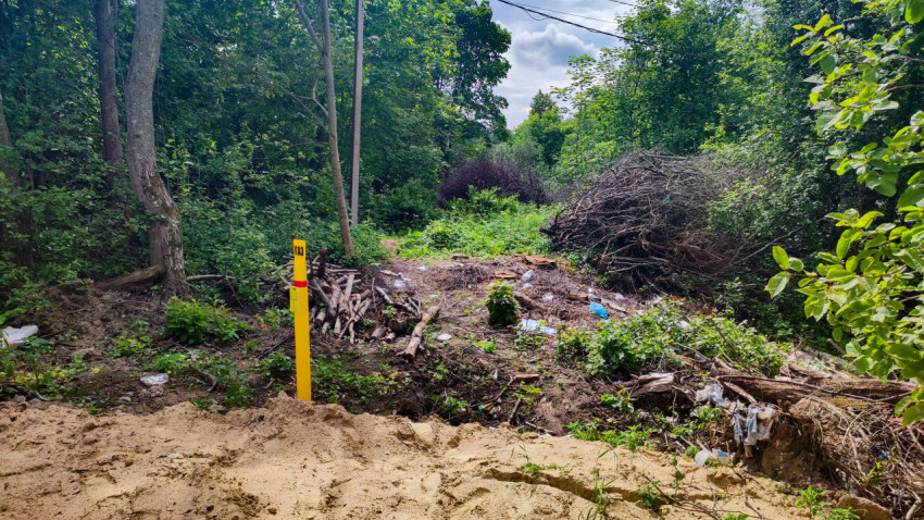 Расчищенная полоса у леса с газовым маркером и кучами веток