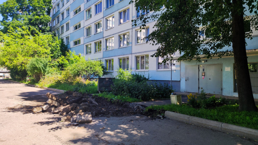 Многоэтажный жилой дом и куча снятого асфальта у дворового проезда