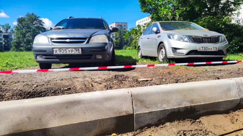 Припаркованные Chevrolet и Kia за сигнальной лентой у нового бордюра