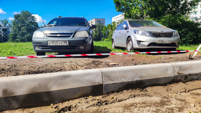 Два автомобиля на дворовой стоянке у ремонтируемого участка с сигнальной лентой