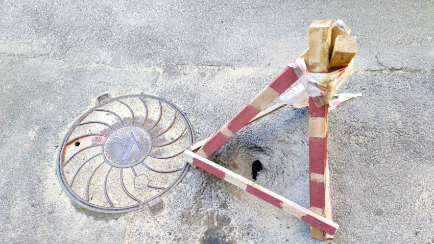 Самодельное ограждение у отверстия в асфальте рядом с люком