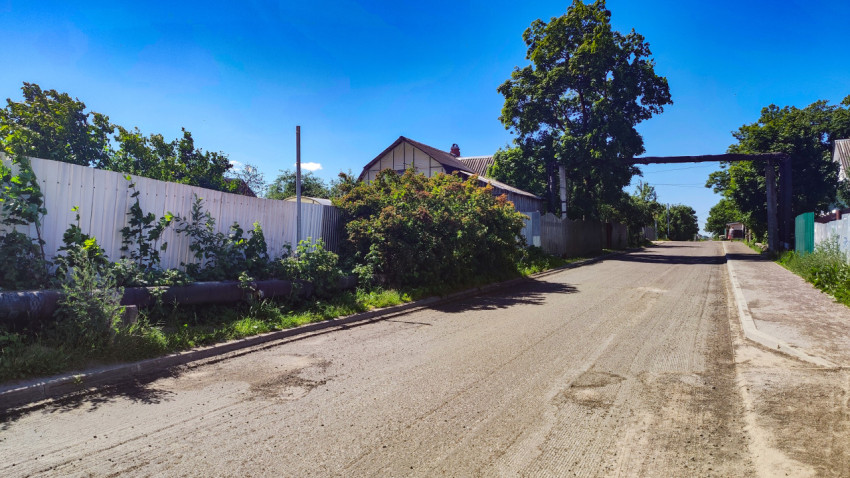 Улица со снятым слоем асфальта и фрезерованным покрытием вдоль ограждений и зелёных насаждений
