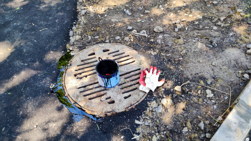 Крышка люка с ведром и перчатками во время ремонтных работ на улице