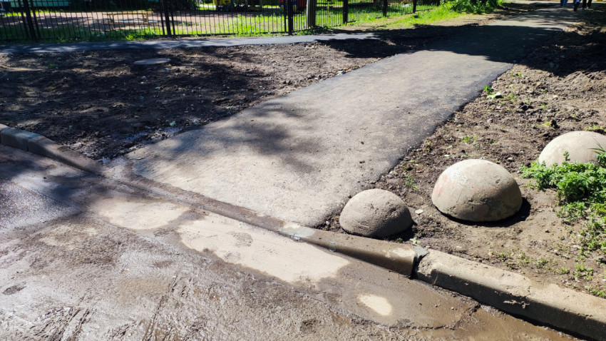 Участок тротуара после ремонта с бордюром и бетонными полусферами