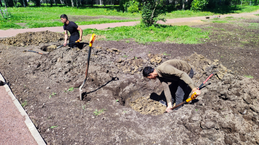 Двое рабочих выполняют земляные работы и формируют котлован во дворе