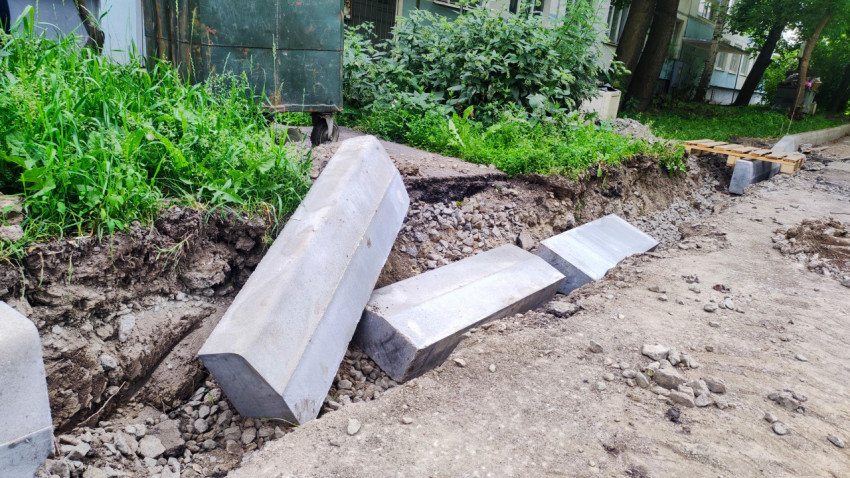 Бетонные бордюрные камни уложены в траншее при ремонте дворового проезда