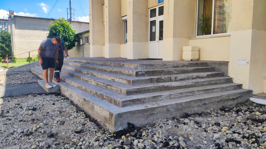 Бетонное крыльцо со ступенями у входа в здание на строительной подсыпке