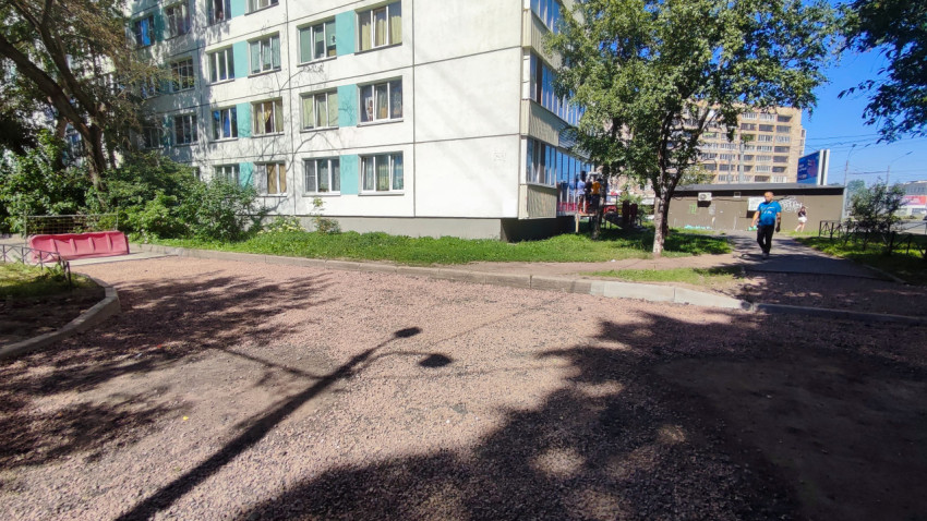 Площадка во дворе с щебёночным основанием и бордюрами у фасада многоэтажного дома