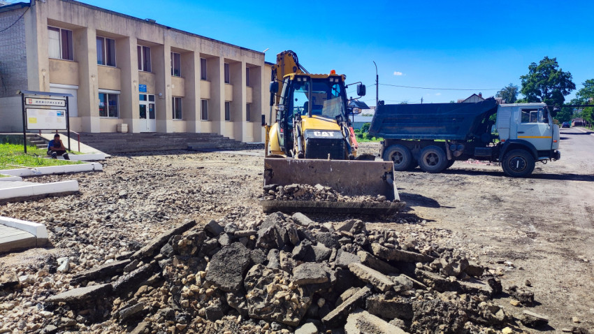 Фронтальный погрузчик и самосвал на строительной площадке рядом с кучей щебня и грунта