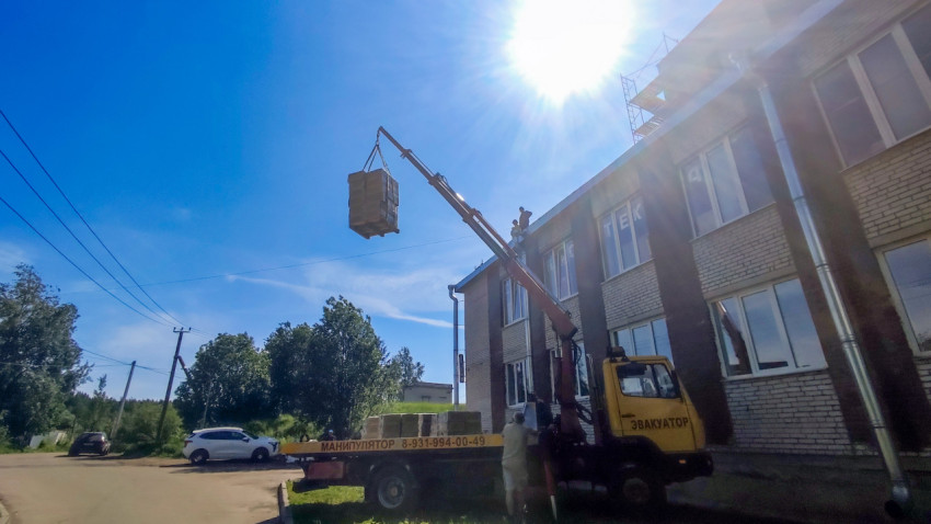 Подъём паллеты краном-манипулятором у кирпичного здания
