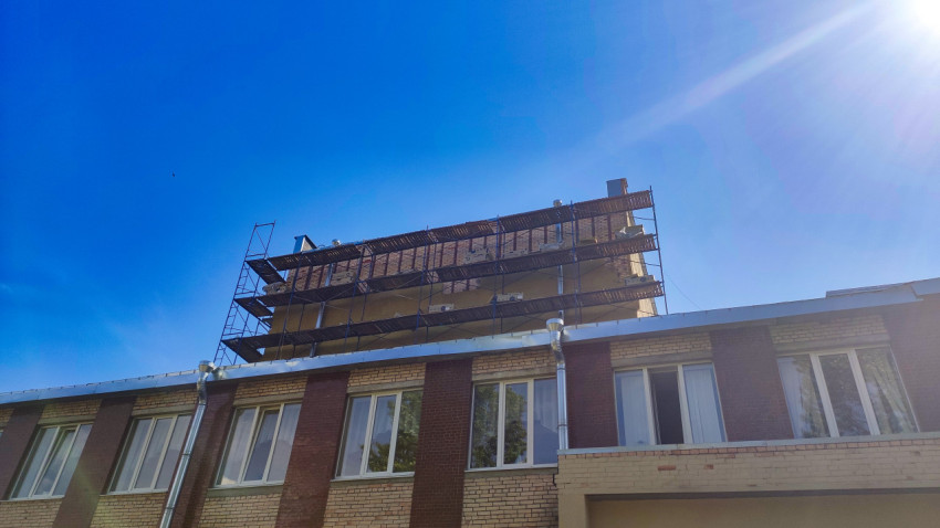 Кирпичное здание со строительными лесами на крыше