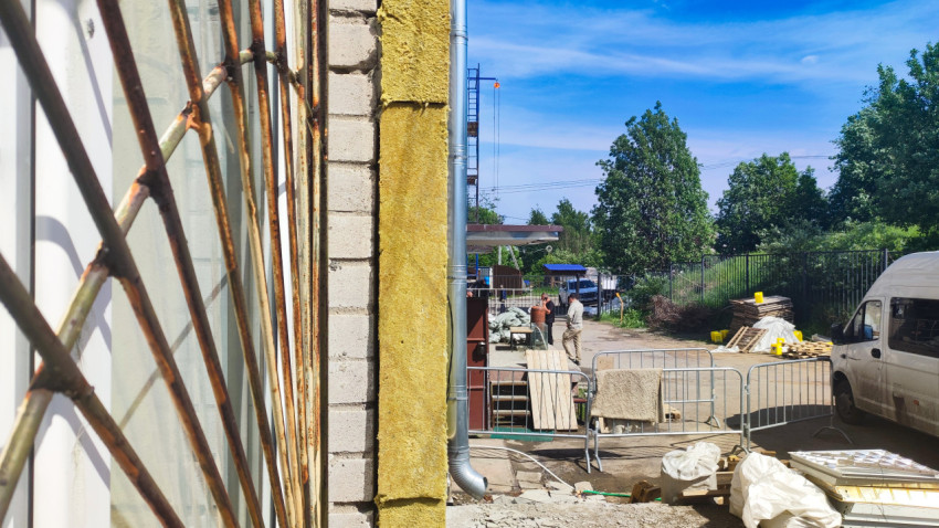 Оконная решётка и полоса утеплителя на углу здания на стройплощадке