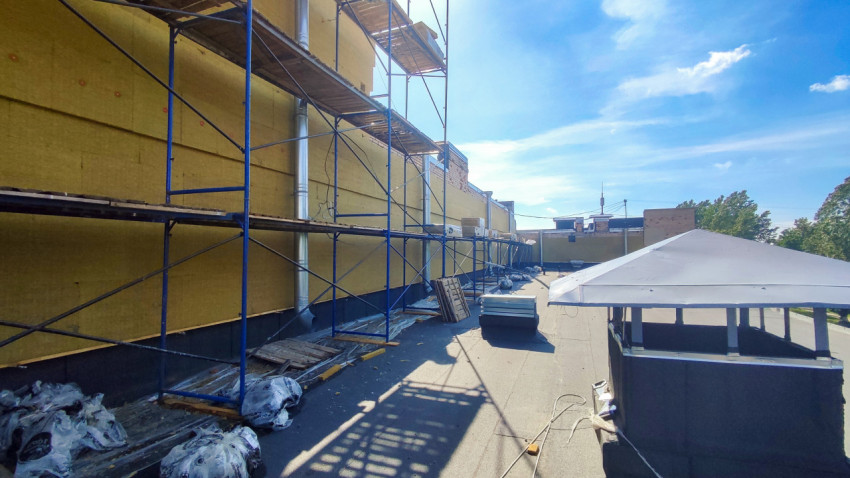 Строительные леса и утепление стены минеральной ватой на плоской крыше здания