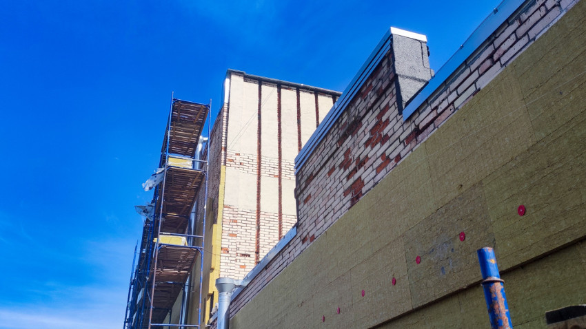 Фасад из кирпича с плитами минеральной ваты и крепежом на этапе наружного утепления