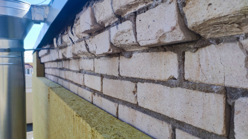 Крупный план кирпичного парапета с гидроизоляцией и слоем минеральной ваты на кровле