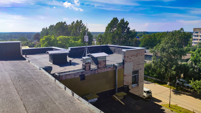 Кровля с вентиляционными шахтами и утепляемым фасадом на фоне зелёного района