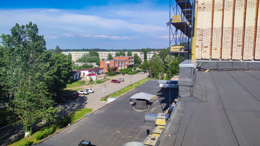 Панорама плоской крыши со строительными лесами и коробками утеплителя у парапета