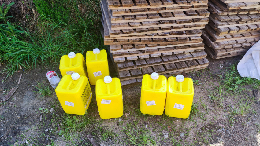 Жёлтые канистры с строительным составом у штабеля деревянных паллет