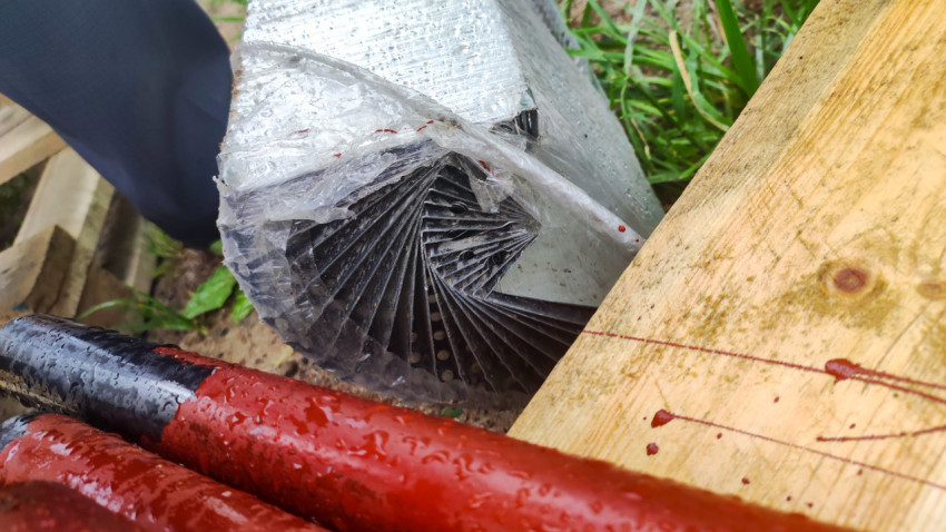 Пачка перфорированных уголков в плёнке рядом с деревянной доской