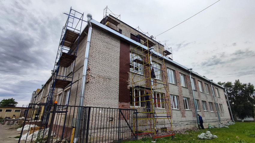 Двухэтажное кирпичное здание со строительными лесами и ремонтом фасада