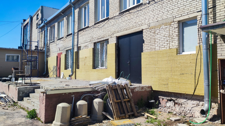 Кирпичное здание с частичным утеплением фасада минераловатными плитами и строительным мусором у входа