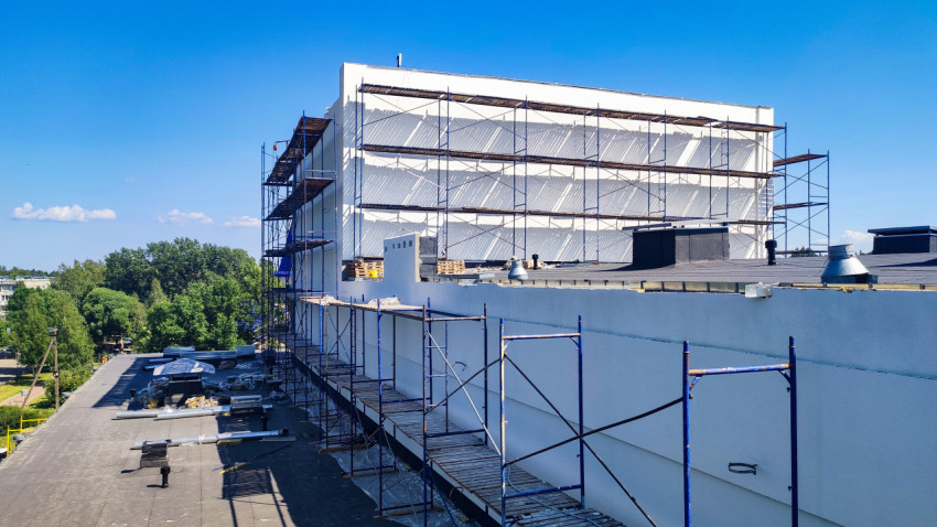 Плоская кровля и фасад здания в ремонте со строительными лесами, поддонами и вентиляционными выходами