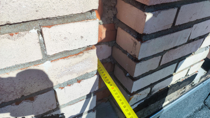 Вертикальный замер рулеткой глубины зазора между кирпичными стенками
