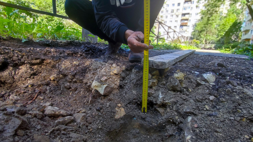 Замер глубины выемки рулеткой рядом с деревянной доской