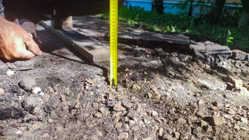 Рулетка в щебёночной подсыпке рядом с фрагментами асфальта и досками