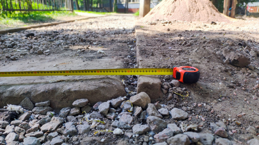 Крупный план рулетки на щебне и бордюре при измерении дорожного основания