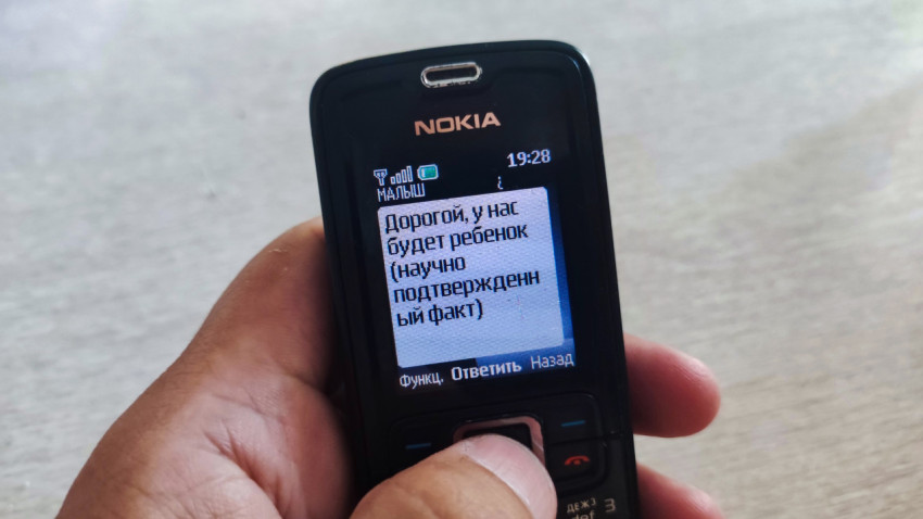 Рука нажимает центральную кнопку телефона Nokia при чтении SMS о ребенке