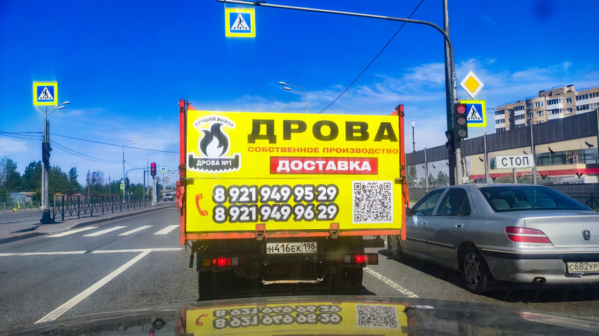 Рекламный баннер «Дрова» на кузове грузовика у светофора с красным сигналом