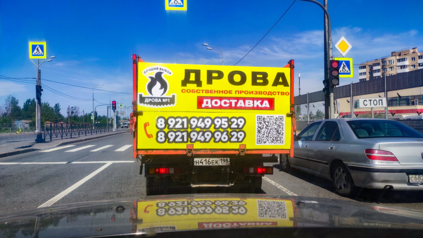 Грузовик с рекламой доставки дров на перекрестке перед пешеходным переходом