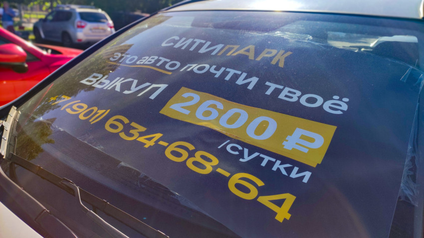 Диагональный крупный план рекламы «Ситипарк» с тарифом «2600 ₽/сутки» на лобовом стекле
