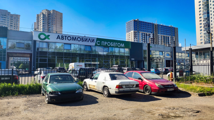 Здание автосалона с вывеской «Автомобили с пробегом» и парковкой машин