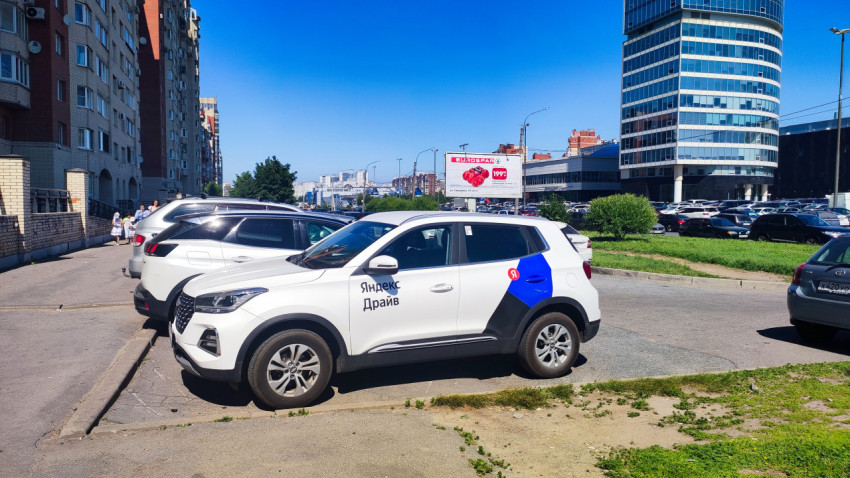 Автомобиль каршеринга «Яндекс Драйв» на парковке у делового квартала и жилых домов