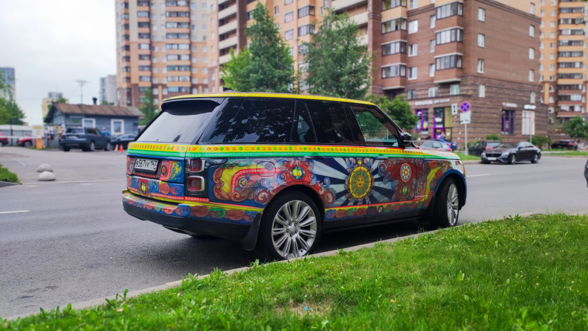 Внедорожник Range Rover с художественной оклейкой на фоне жилых домов и перекрёстка