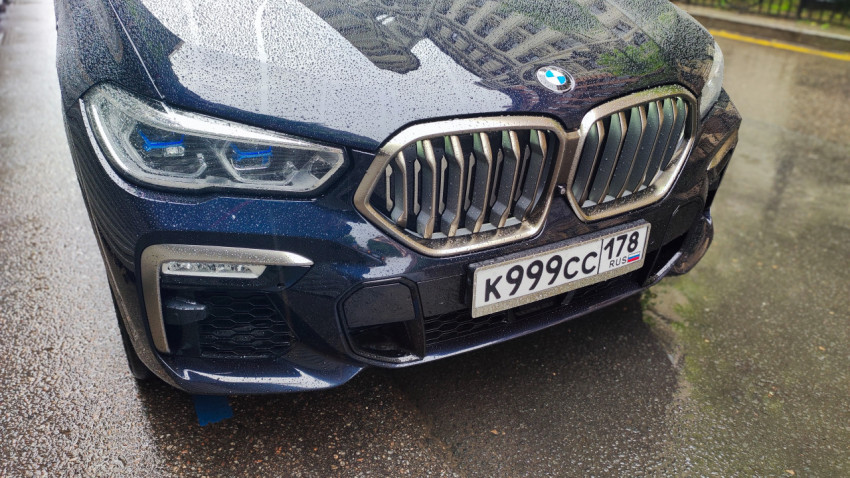 Передняя часть BMW с решёткой радиатора и фарой в каплях дождя крупным планом